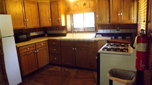 Una cocina con gabinetes de madera, estufa, refrigerador y extintor.