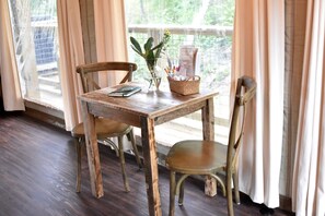 A wooden table with chairs, a vase with a plant, and a basket with stationery.