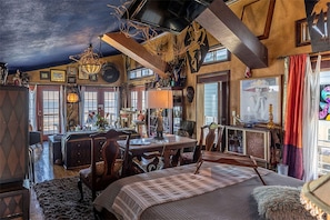 A room with a bed, a desk, and a dining area. There are various decorations and furniture. - Romantic Open-Concept Couples Suite with Private Jacuzzi & Balcony Views in Bacliff, Texas (Bacliff)