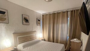 A bedroom with a bed, bedside tables, a lamp, curtains, and wall art. - Charming 1-bedroom Apartment in the Heart of Madrid (Madrid)
