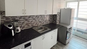 A modern kitchen with a washing machine, a sink, and a microwave. - Charming 1-bedroom Apartment in the Heart of Madrid (Madrid)