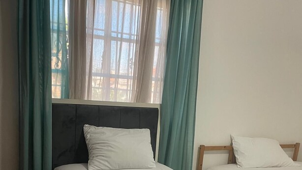 A room with two beds, a window with curtains, and a view of the outside. - Charming 1-bedroom Apartment in the Heart of Madrid (Madrid)