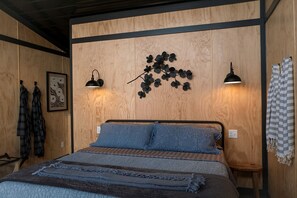 Ein Schlafzimmer mit einem Bett, zwei Wandlampen, einem Wandbild und einem karierten Handtuch an der Wand.