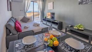 Un saló modern amb un sofà, taula de dinar i vista al mar.