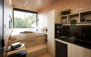 A compact room with a bed, a small table, and a kitchenette.