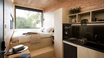 A compact room with a bed, a small table, and a kitchenette.