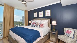 A bedroom with a bed, a chair, a nightstand, a ceiling fan, and a window with curtains. - New to Program - Silver Shells St. Lucia 602 (Destin)