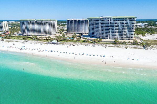 A beachfront hotel with multiple high-rise buildings, a sandy beach, and clear turquoise waters. - New to Program - Silver Shells St. Lucia 602 (Destin)