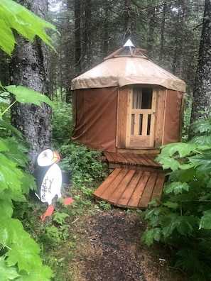 Una casa en un árbol de madera con un pequeño porche, rodeada de un bosque denso.