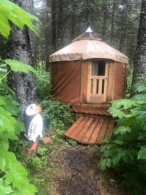 Ein hölzernes Baumhaus mit einer kleinen Veranda, umgeben von dichtem Wald.