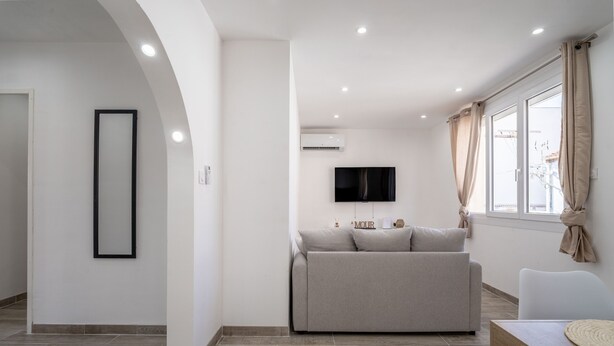 Una sala de estar moderna con un sofá, un televisor y una ventana con cortinas.