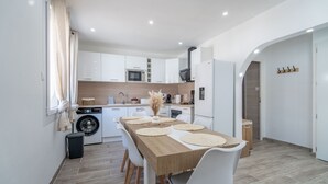 Una cocina moderna con armarios blancos, una mesa de comedor de madera y una lavadora.
