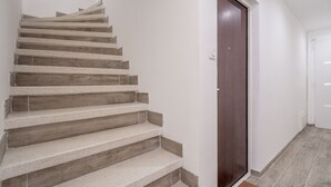 Una escalera con acabado de madera, una puerta de madera oscura y una pared blanca.