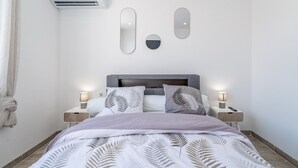 Un dormitorio con cama, mesitas de noche, espejos en la pared y un equipo de aire acondicionado.