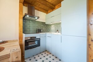 Eine kompakte Küche mit Einbauofen, Mikrowelle und Spüle.