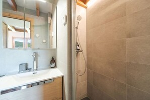 Une salle de bain équipée d’une douche, d’un lavabo, d’un miroir et d’un porte-serviettes.
