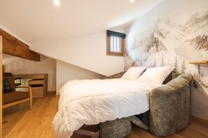 Une chambre à coucher comprenant un lit, une chaise, un bureau et une fresque murale représentant un paysage de montagne.