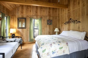 Una habitación con paneles de madera, una cama, una silla, una mesa y un ventanal.