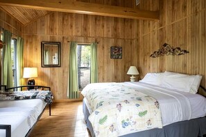 Habitació amb panells de fusta, un llit, una cadira, un taulell i una finestra.