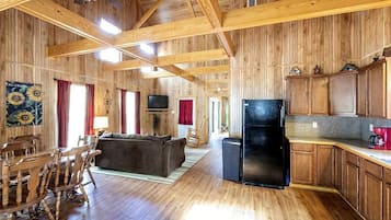 A log cabin interior with a dining area, living room, and kitchen.