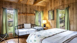 A wooden-paneled room with two beds, a nightstand, and a window with curtains. - Peaceful Waterfront Cabin with Private Pond Near Zwolle, Louisiana (Zwolle)