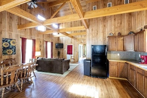 A log cabin interior with a dining area, living room, and kitchen.