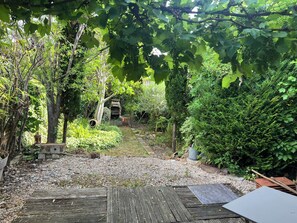 Ein Garten mit einer Holterrasse, einem Backofen aus Ziegeln und verschiedenen Pflanzen.