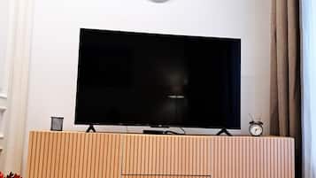 Una TV a schermo piatto su un mobile in legno, con una sveglia sopra.