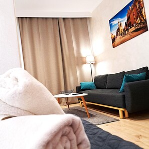 Ein modernes Wohnzimmer mit einer Couch, einem kleinen Tisch, einer Lampe und einem Bild an der Wand.