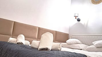 Un letto rifatto con copriletto trapuntato, una testiera e un portalampada a parete.