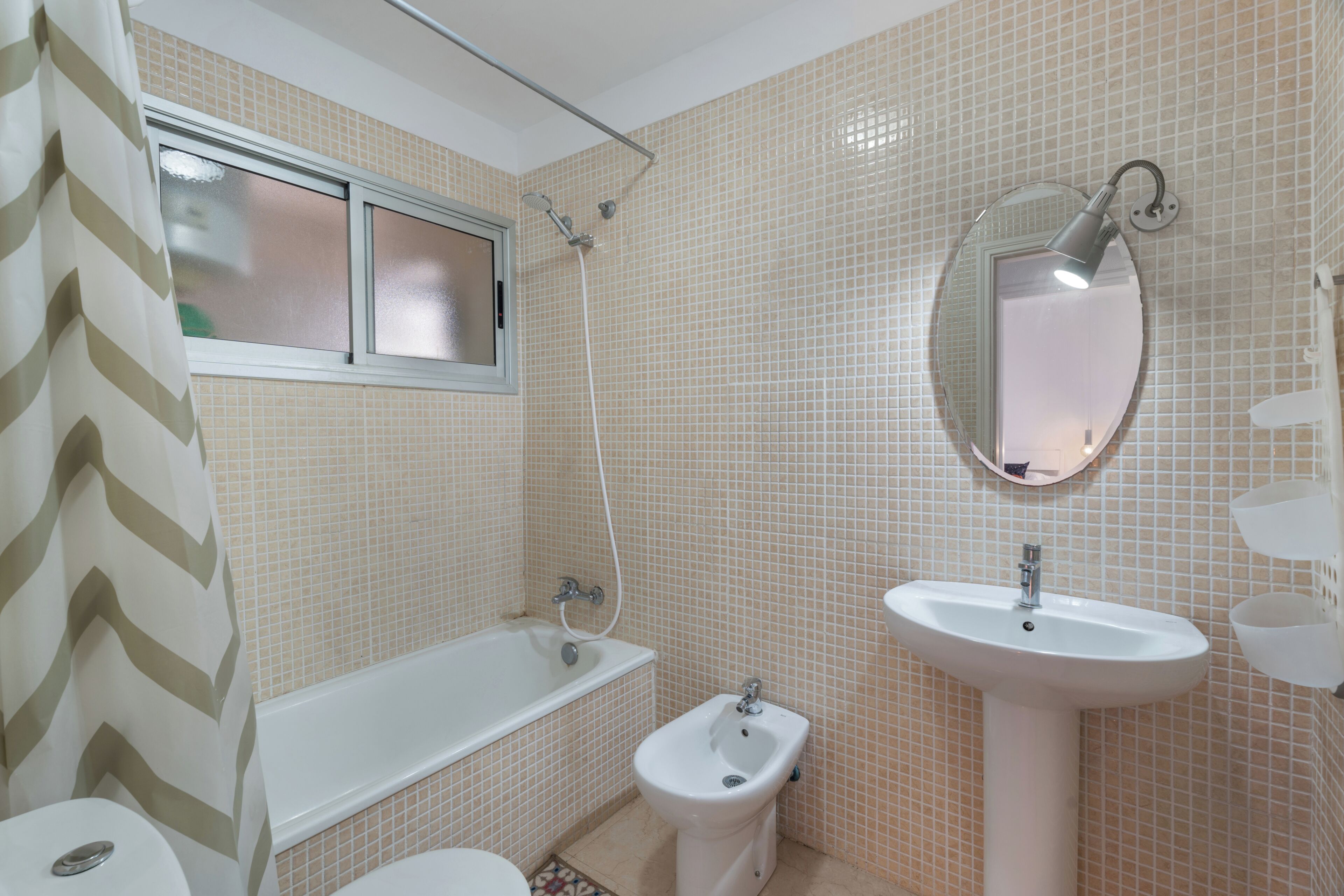 A bathroom with a bathtub, bidet, sink, and a mirror.
