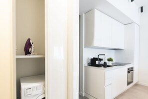 A modern kitchen with white cabinetry, a built-in oven, and a coffee maker. - GuestHost - Comfy ARIA Apartment near Cenisio (MM5) (Milan)