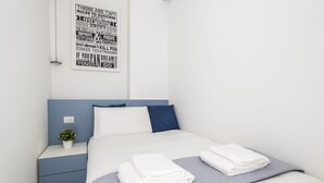 A neatly made bed with folded white towels, a small bedside plant, and a motivational quote poster on the wall. - GuestHost - Comfy ARIA Apartment near Cenisio (MM5) (Milan)