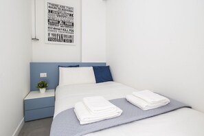 A neatly made bed with folded white towels, a small bedside plant, and a motivational quote poster on the wall. - GuestHost - Comfy ARIA Apartment near Cenisio (MM5) (Milan)
