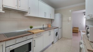 A modern kitchen with white cabinets, a built-in oven, a microwave, a sink, and a washing machine. - Erma Sun & Pool - Apartment in Candelaria (Candelaria)