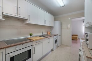 A modern kitchen with white cabinets, a built-in oven, a microwave, a sink, and a washing machine. - Erma Sun & Pool - Apartment in Candelaria (Candelaria)