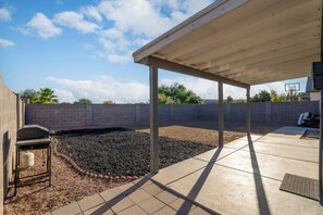 Ein überdachter Patio-Bereich mit Betonboden, Grill und Backsteinmauer.