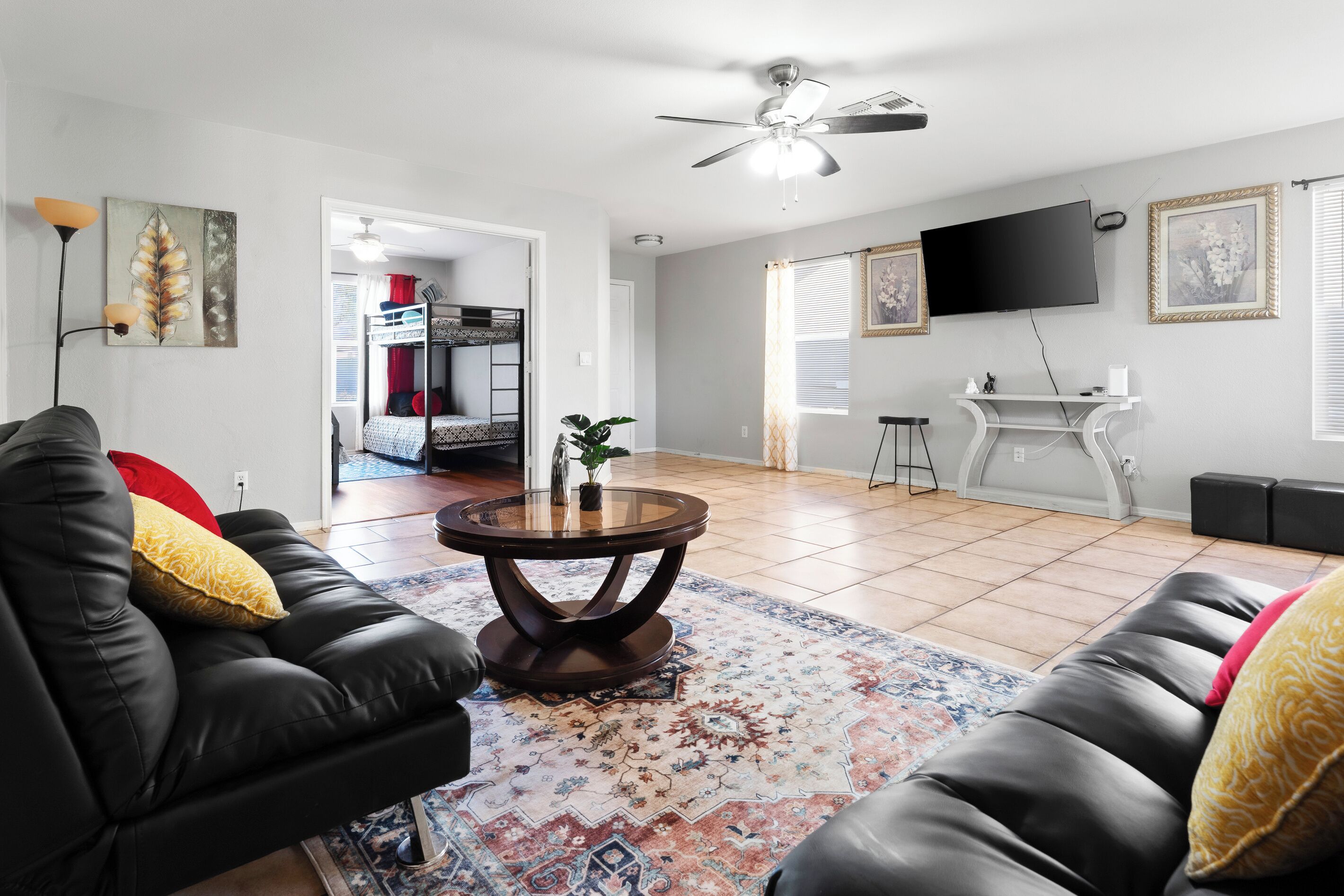 A living room with a sofa, a coffee table, a TV, and a ceiling fan.