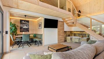 A spacious living area with a wooden staircase, a dining area, and a kitchen.