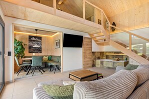 Un vaste espace de vie comprenant un escalier en bois, un coin repas et une cuisine.