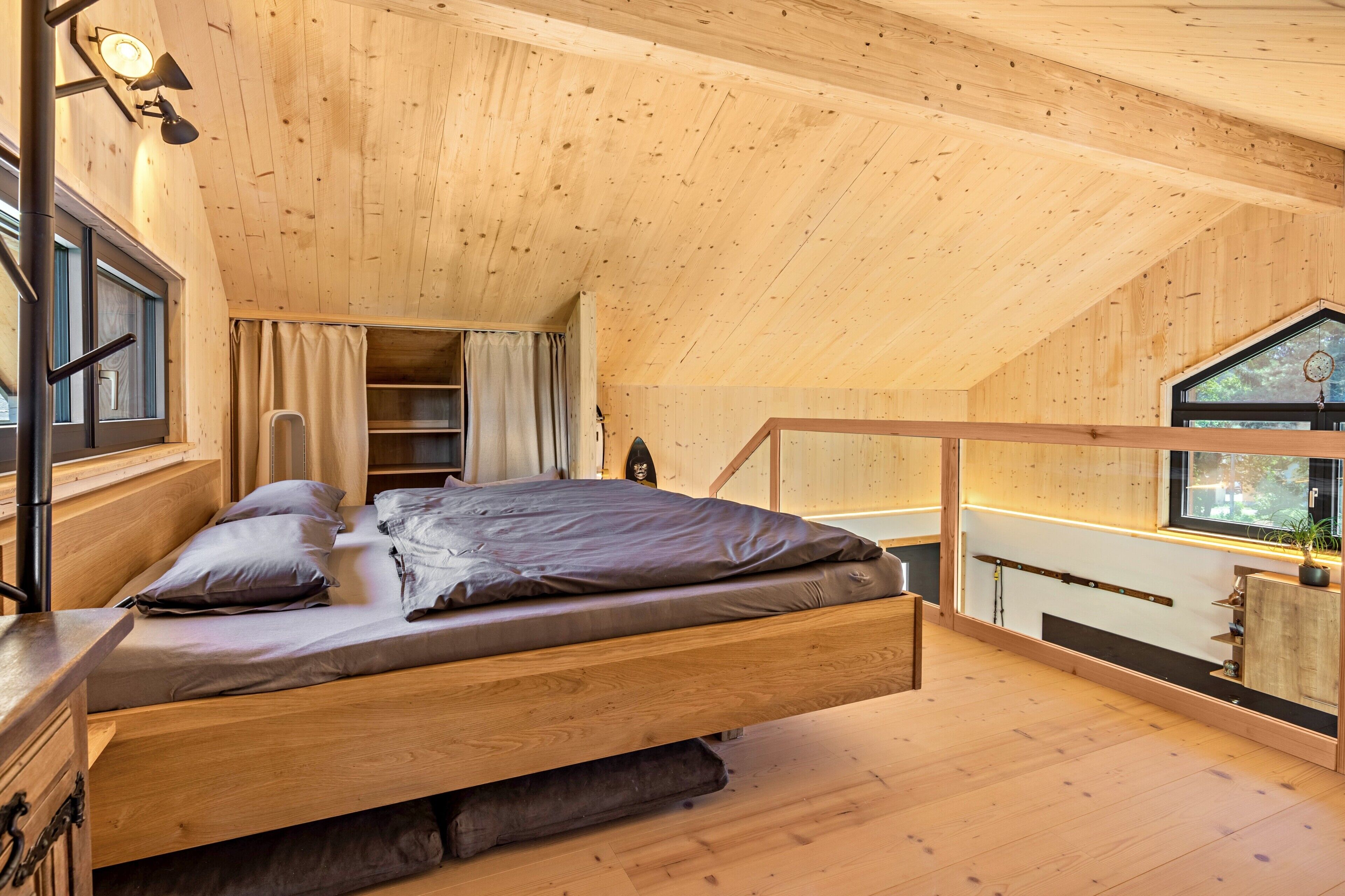 Ein Schlafzimmer im Loft-Stil mit Holzbalkendecke, einem Bett, einem Fenster und einer Treppe.