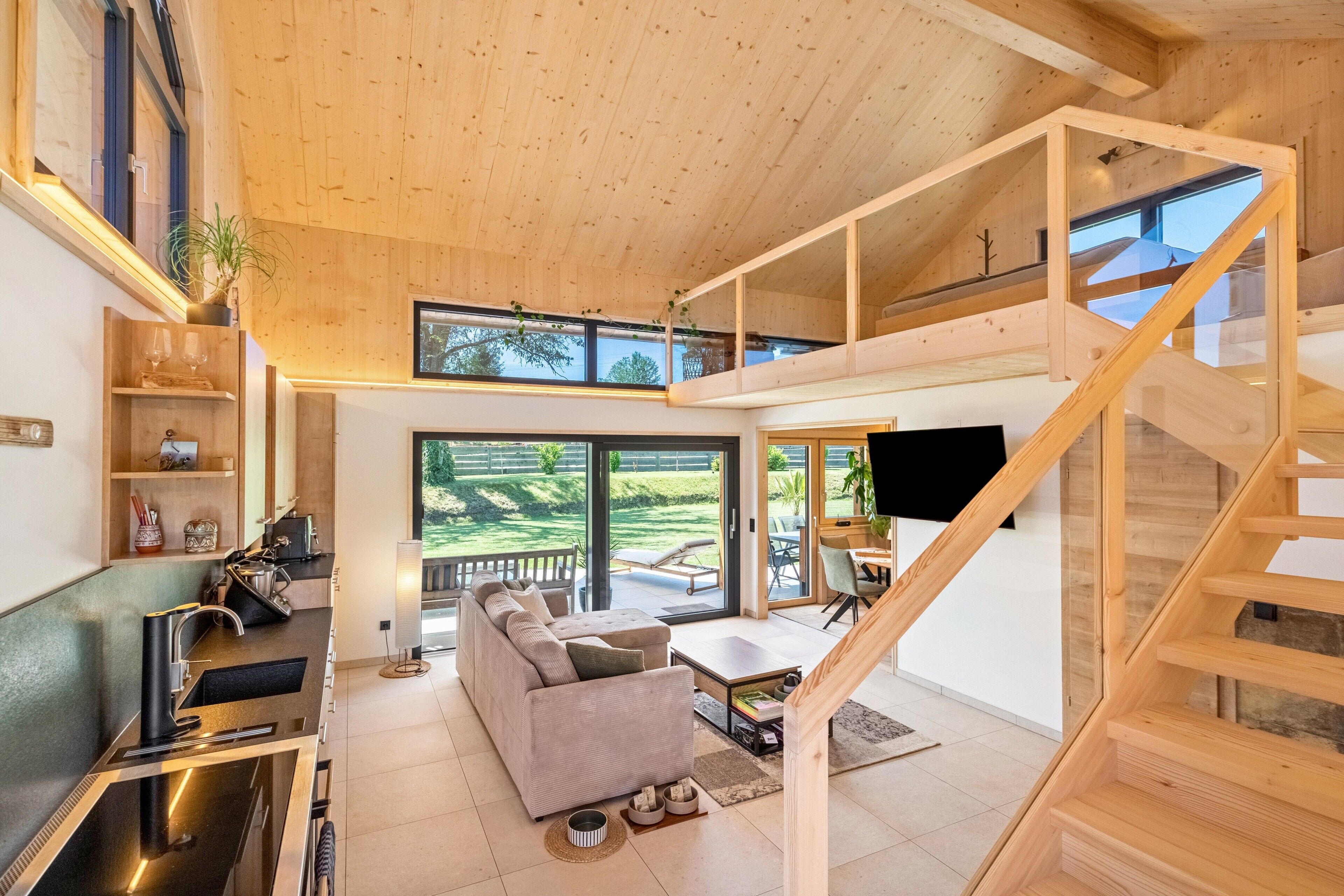 Un interior moderno con cocina, sala de estar y una escalera que lleva a un nivel superior.