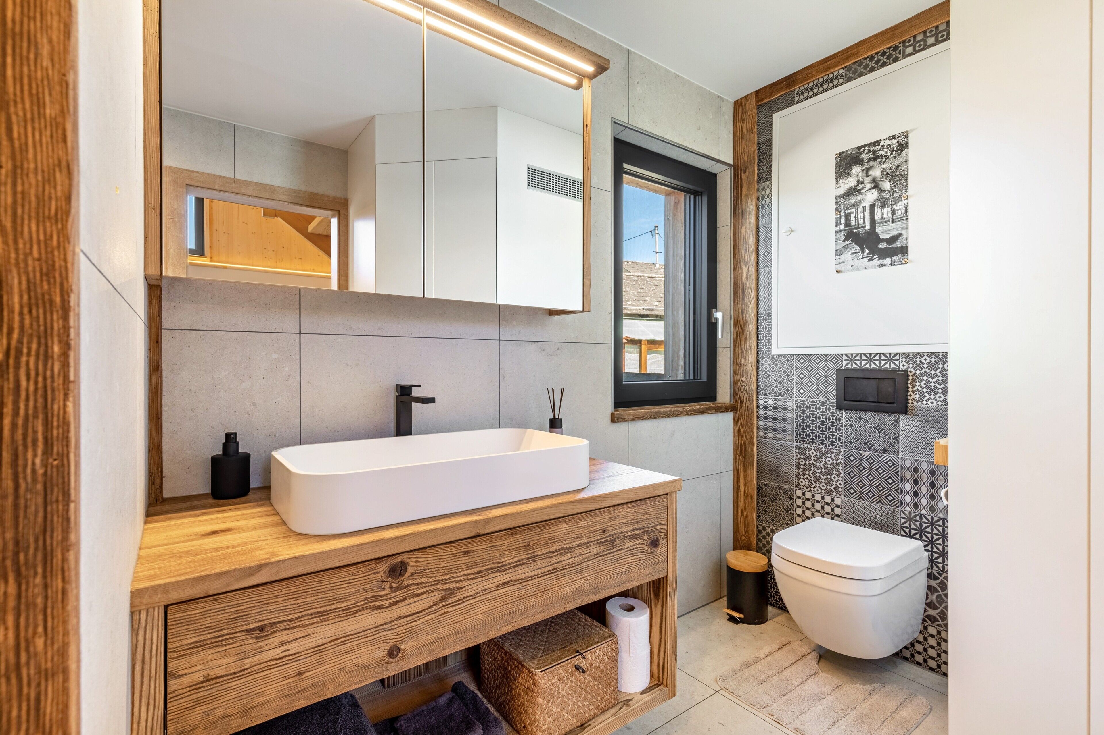 Ein modernes Badezimmer mit einem Holzlagerflächen, einem großen Spiegel und einer Toilette.