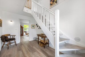 A staircase with white railings, a wooden bench, and a small table with baskets. - Beautiful holiday home, completely renovated in 2026, located in scenic. (Sønder Felding)