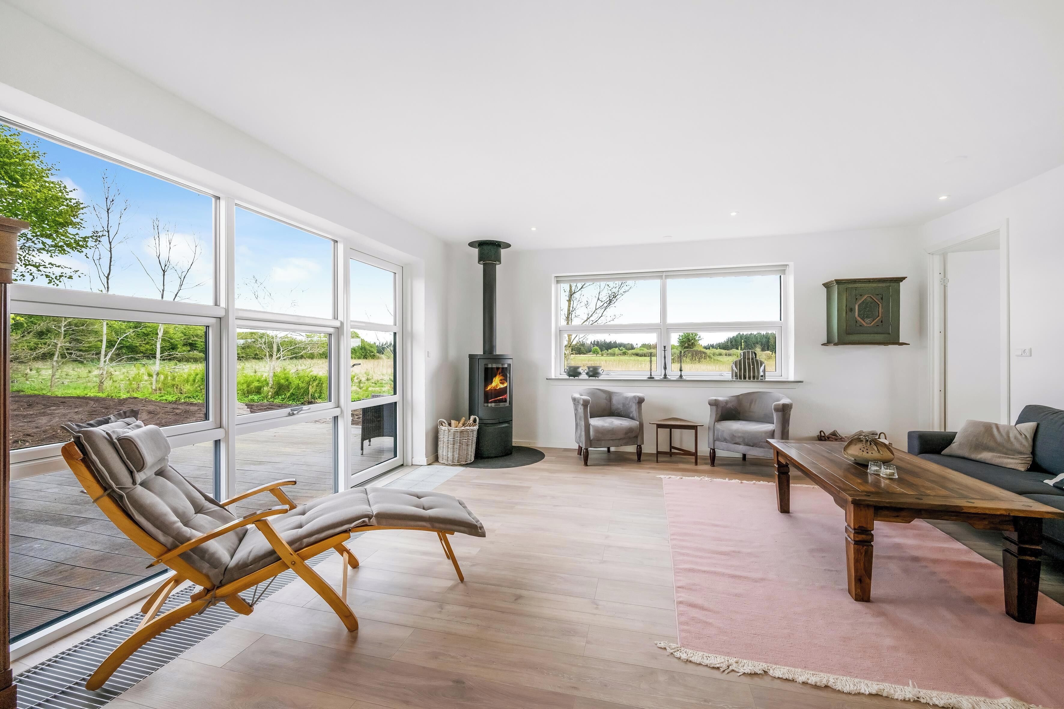A spacious living room with large windows, a fireplace, and modern furniture.