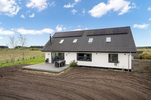 A modern house with a sloped roof, solar panels, and a patio with outdoor furniture. - Beautiful holiday home, completely renovated in 2026, located in scenic. (Sønder Felding)