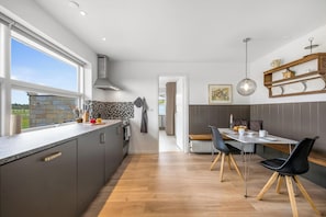 Una cocina moderna con un amplio ventanal, una zona de comedor con mesa y sillas, y vistas al exterior.
