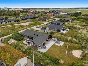 Ein Wohngebiet mit Häusern im modernen Stil, einer grünen Landschaft und blauem Himmel.