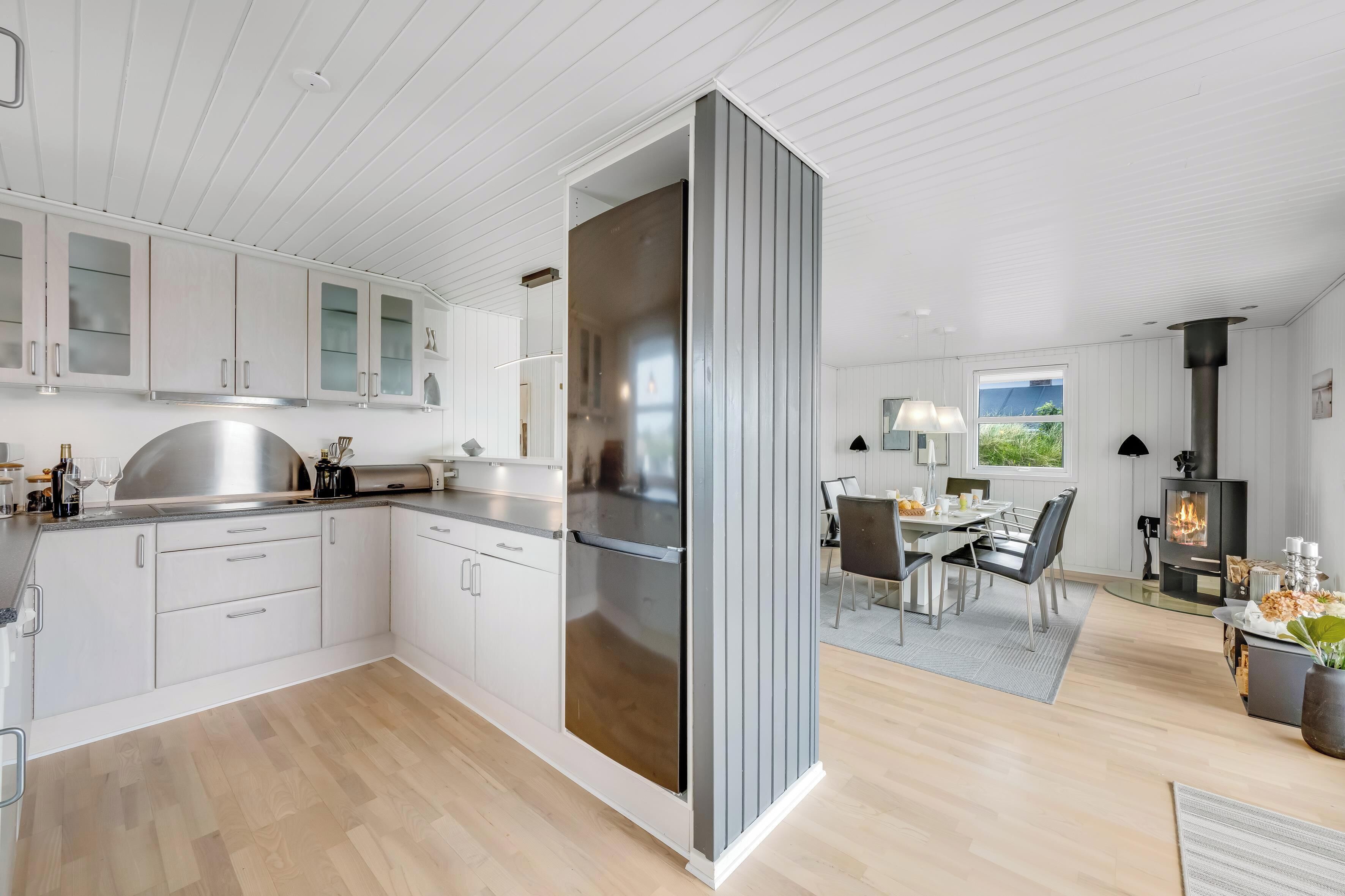 Eine moderne Küche mit weißen Schränken, einem Edelstahlkühlschrank und einem Essbereich mit Tisch und Stühlen.