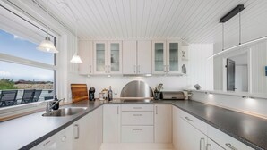 A modern kitchen with white cabinets, a stainless steel range hood, and a large window overlooking a scenic view. - Lovely holiday home with a wilderness bath, close to the North Sea and. (Ringkøbing)